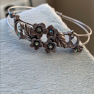 Silver bracelet with floral design and jewels.
